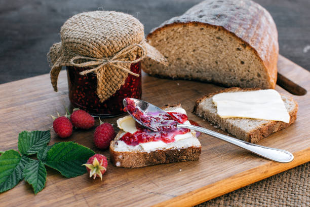 istock Raspberry jam and bread with butter in a jar on the wooden table Lunch breakfast 695971070