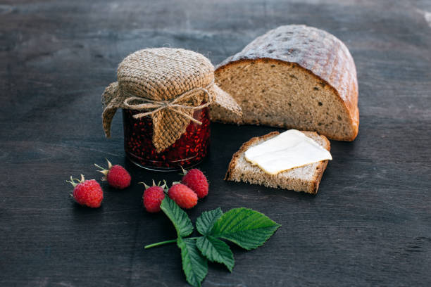 istock Raspberry jam and bread with butter in a jar on the wooden table Lunch breakfast 695971114