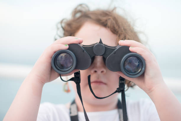 istock Beautiful young girl on boat looking directly at camera through binoculars 695978488