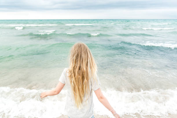 istock Young blonde girl standing on the beach 695979878