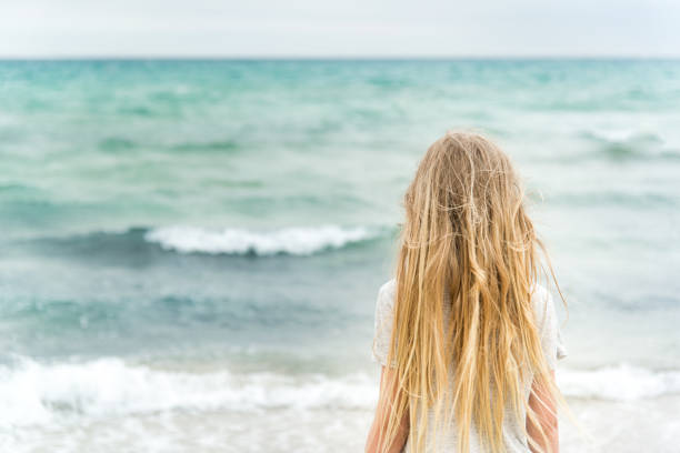 istock Young blonde girl standing on the beach 695980158