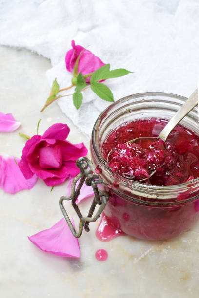 istock Glass jar and little spoon with tea rose petal jam on light marble background. Copy space for text. 695984228