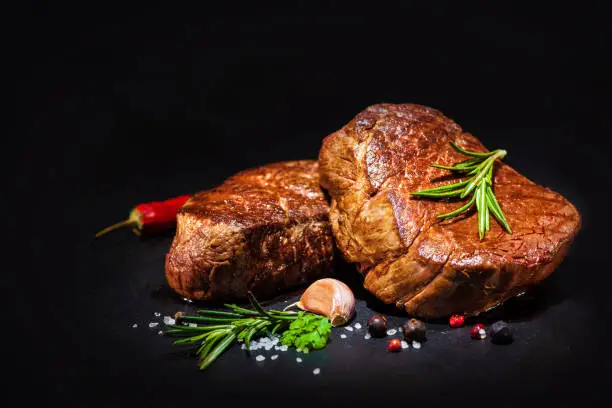 grilled beef fillet steaks with spices on dark background