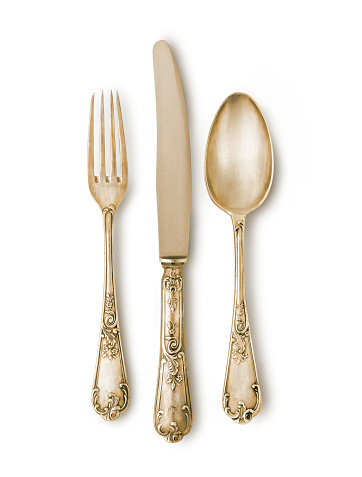 Gold cutlery set against white background with a soft shadow. Fork,knife and spoon. Really ancient marks and texture. Clipping path