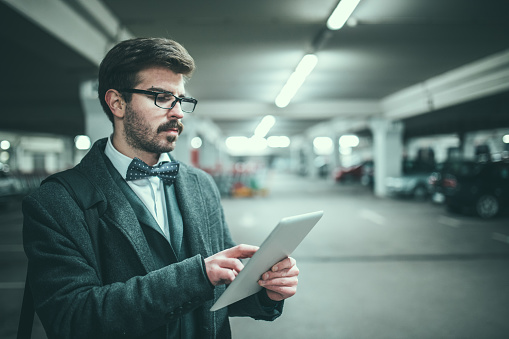 Businessman on parking lot at night and using digital tablet