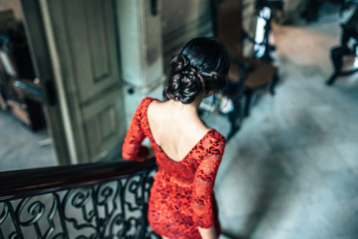 beautiful young cuban woman in red dress going down stairs in old house