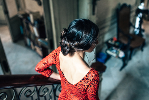 beautiful young cuban woman in red dress going down stairs in old house