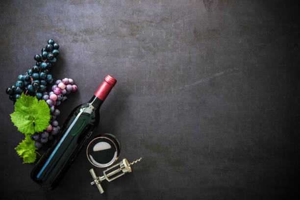 Bottle of red wine, wineglass and grapes Bottle of red wine, wineglass, grapes and corks on dark background restaurant table card stock pictures, royalty-free photos & images