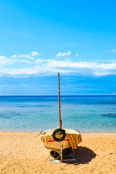 an old fishing boat stranded in the quiet beach Platja de Sa Caleta in Lloret de Mar, in the Costa Brava, Spain