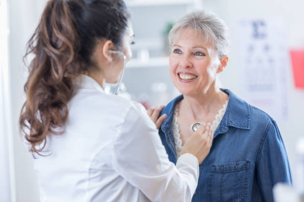 mujer médico escucha al corazón del paciente mayor - patient doctor hospital senior adult fotografías e imágenes de stock