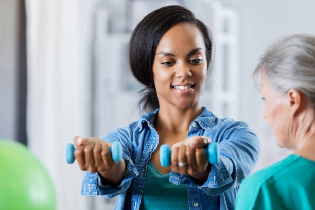 istock Woman lifts hand weights in physical therapy session 696021848