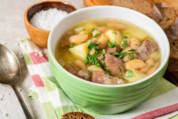 istock Beef soup with potatoes, beans and leeks in ceramic bowl on stone background. 696034904