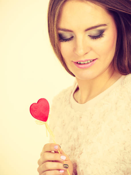 istock Beautiful woman holding heart shaped hand stick 696035688