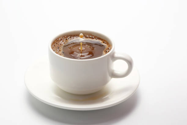 istock drop of milk falling in a white cup with black coffee 696042850