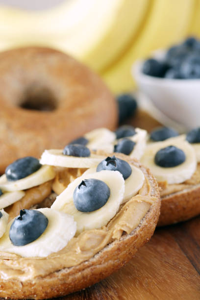 Banana, blueberries and peanut butter on wholemeal bagels - shallow dof stock photo