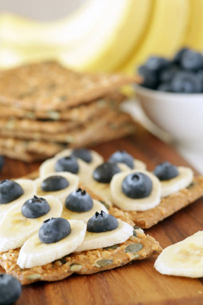 Banana and blueberries on pumpkin seeded crackers - shallow dof stock photo