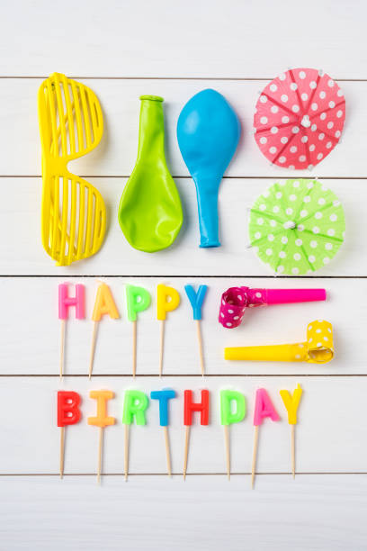 Birthday accessories on white wooden table. Top view