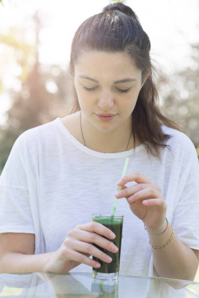istock Young woman drinking spirulina drink 696053092