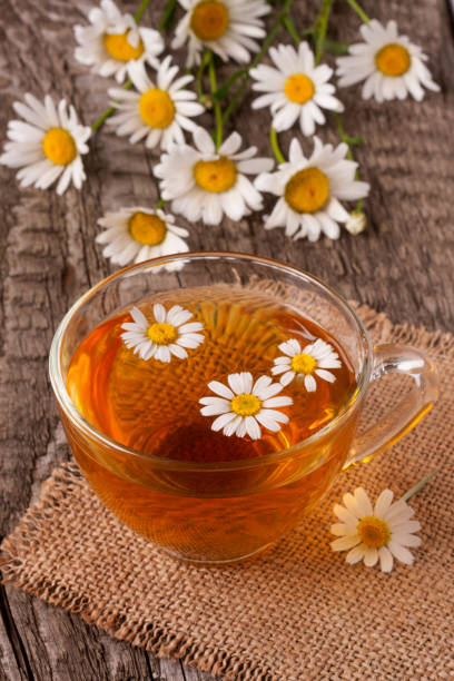 istock Herbal tea with fresh chamomile flowers on old wooden background 696056782