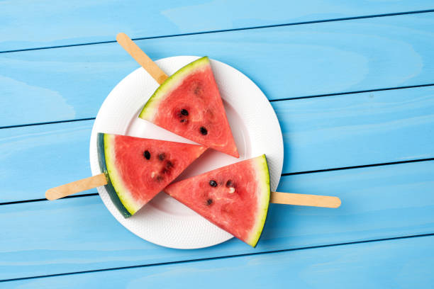 istock Watermelon slices on blue wooden table. 696071048