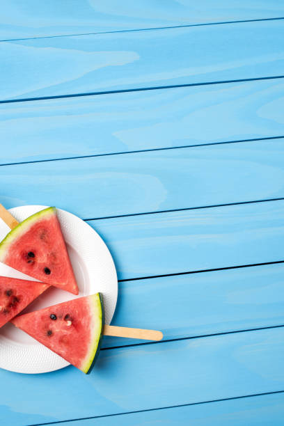 istock Watermelon slices on blue wooden table. 696071150