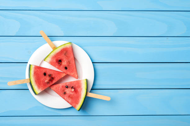 istock Watermelon slices on blue wooden table. 696071240
