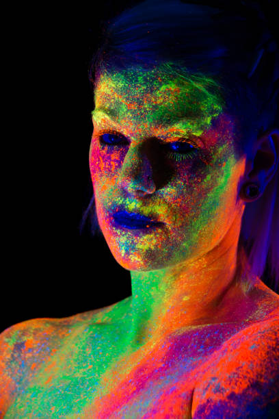 istock Closeup of model in multicoloured UV face paint with eyes blue, vertical 696081254
