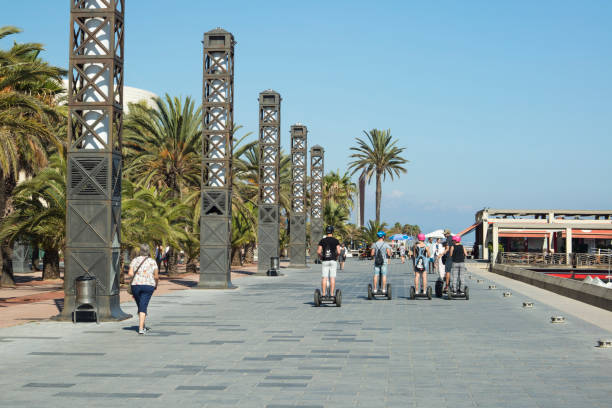 grupo de turistas em segways andar em uma passarela de pedestre em port olimpic em barcelona - segway - fotografias e filmes do acervo