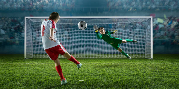 joueur de football enfants marquant un but. le gardien essaie de frapper la balle - penalty shot photos et images de collection