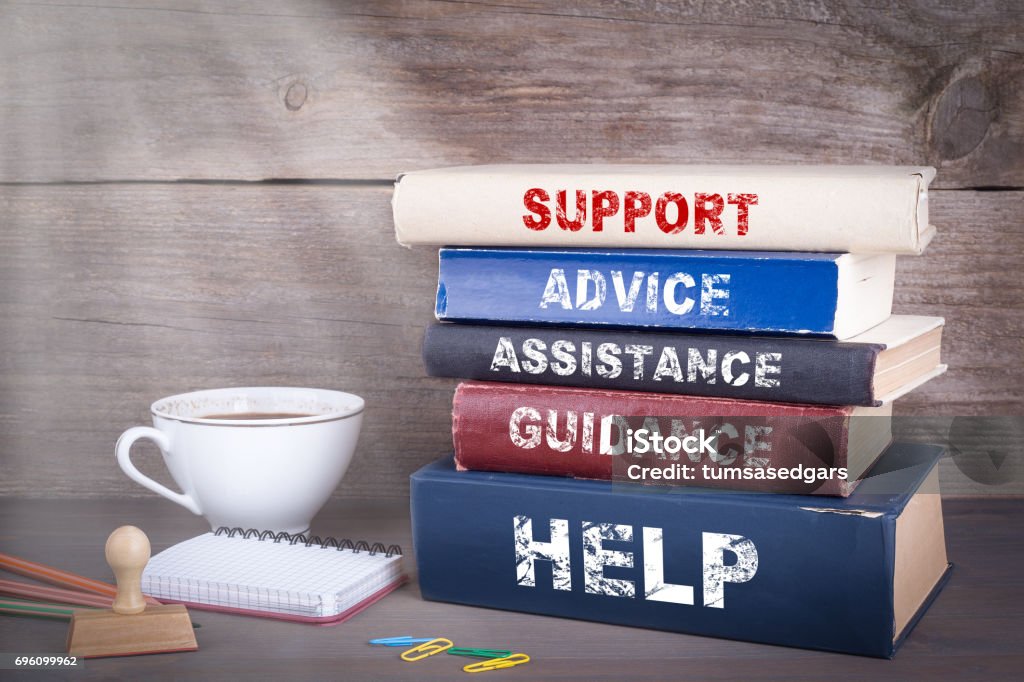 Support concept. Stack of books on wooden desk Advice Stock Photo