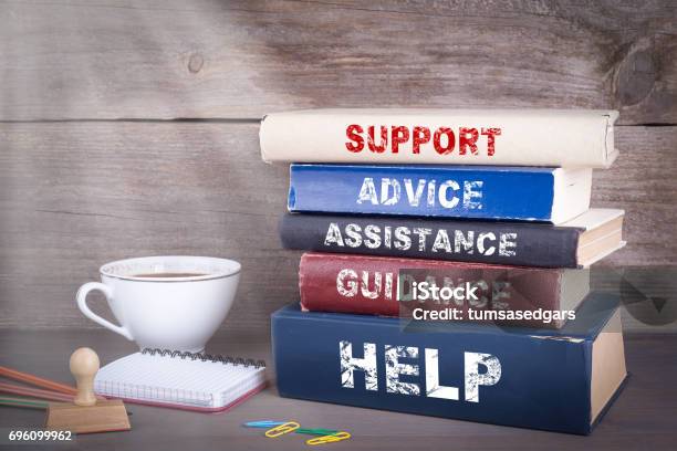 Support Concept Stack Of Books On Wooden Desk Stock Photo - Download Image Now - Advice, Support, Assistance