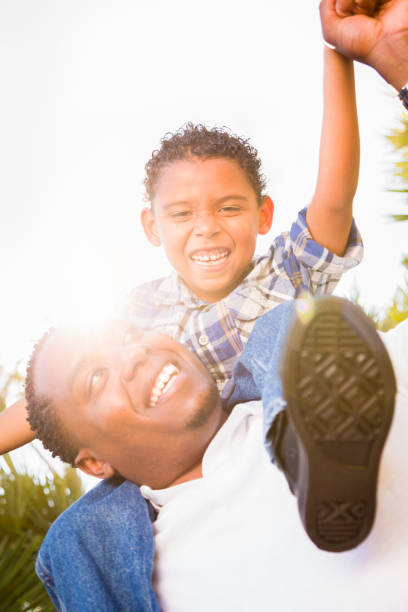 istock Mixed Race Son and African American Father Playing Piggyback Outdoors Together. 696100528