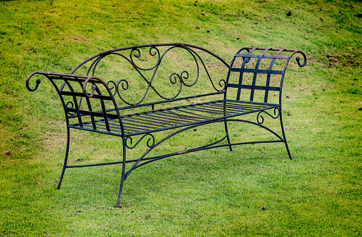 Metal park bench on green grass in the park