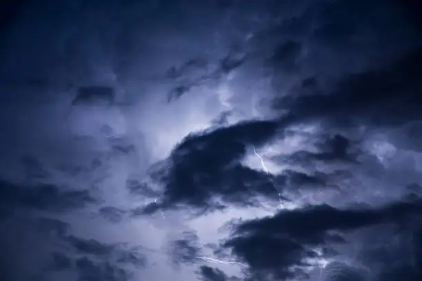 Real lightning bolt flashes in night storm with dark clouds - halloween background.