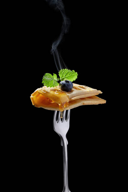 gofres belgas con miel y arándanos en la horquilla, aislada en negro. dulces divertidos. - waffle belgian waffle belgian culture isolated fotografías e imágenes de stock