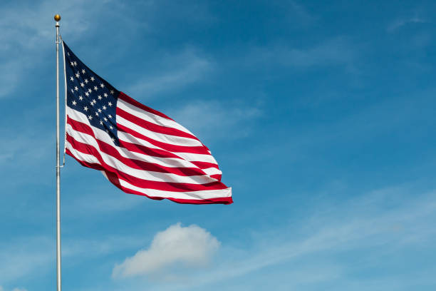 istock American Flag with Blue Sky and Clouds 696130240