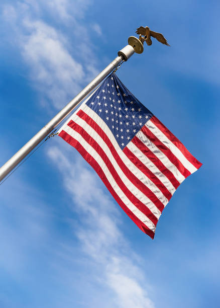 istock American flag on pole waving in the wind against blue sky 696143664
