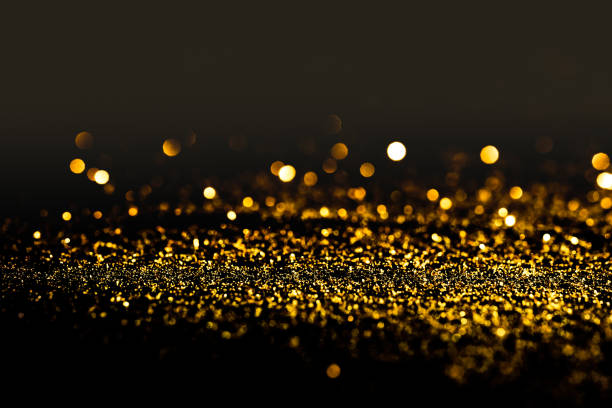 Sprinkle gold dust on a black background in the dark