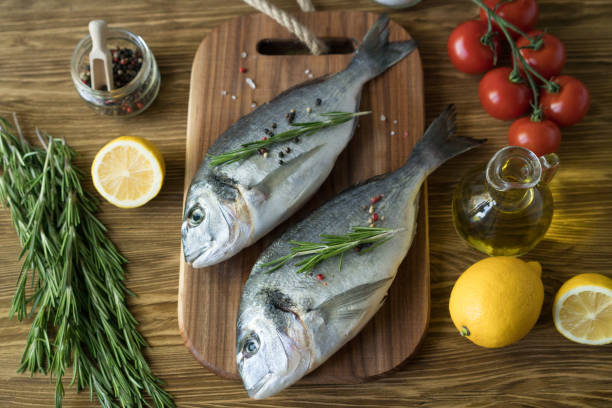 istock Raw fish cooking and ingredients. Dorado, lemon, herbs and spices. 696155338