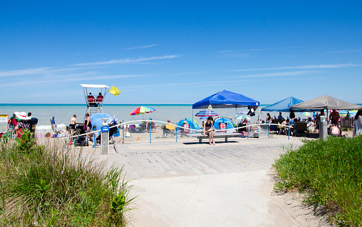 Grand Bend Ontario, Canada - July 02, 2016: Unidentified people and lifeguards in the beach of the lake Grand Bend in leisure activities in summertime in a deep blue sky as editorial