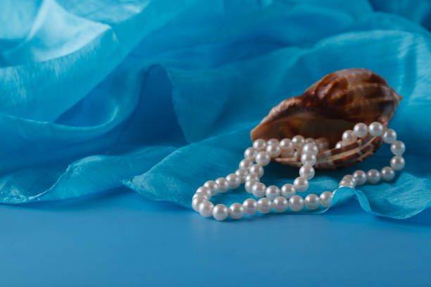 Pearl and Shell, Paua shell and pearl ornaments on blue drapery