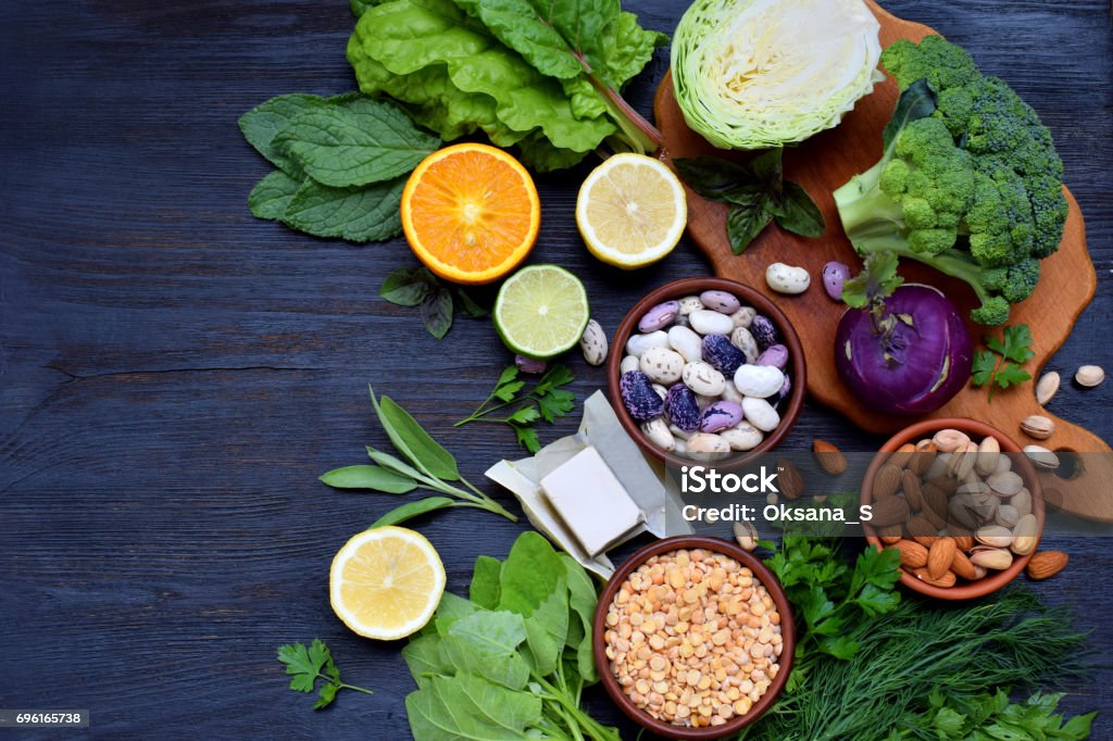 Composition on a dark background of products containing folic acid, vitamin B9 - green leafy vegetables, citrus, beans, peas, nuts, yeast. Top view. Flat lay Folic Acid Stock Photo