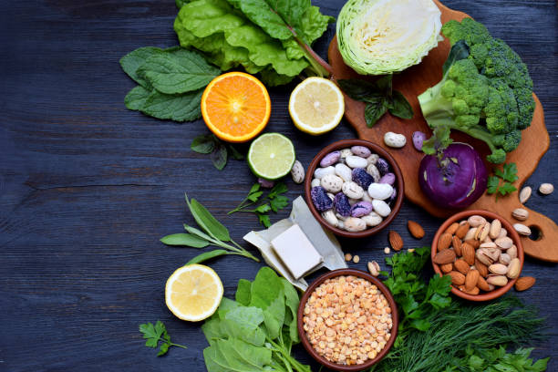 composição em um fundo escuro de produtos contendo ácido fólico, vitamina b9 - vegetais de folhas verdes, citros, feijão, ervilhas, nozes, levedura. vista superior. estabelecer o plano - ácido fólico - fotografias e filmes do acervo