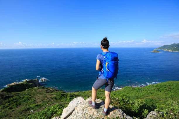 istock successful woman backpacker enjoy the view on seaside mountain rock 696169018