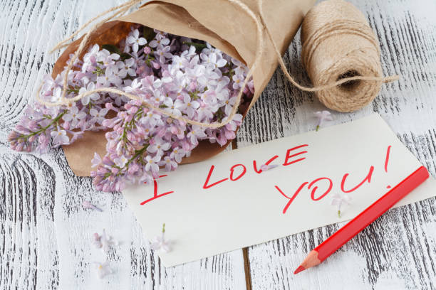 istock Fresh violet lilac flowers and tag on grey textured background 696169798