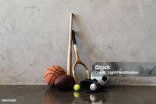 Opinión Del Primer De Varias Pelotas Y Equipo Junto A La Pared Gris De Deportes Foto de stock y más banco de imágenes de Deporte