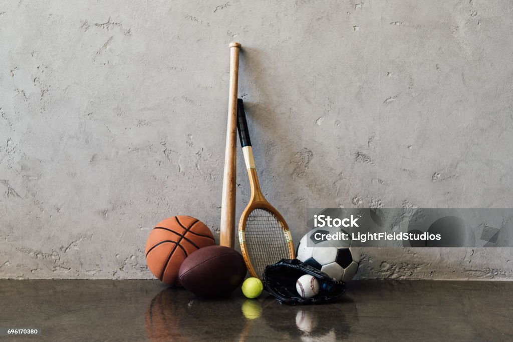 Vue rapprochée de plusieurs balles et équipement près de mur gris de sport - Photo de Sport libre de droits