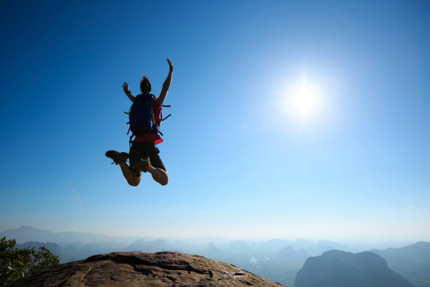istock cheering woman backpacker jumping on sunrise mountain top 696170384