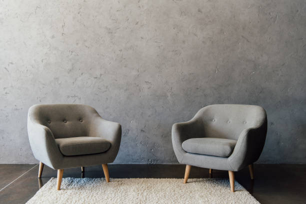 istock Two cozy grey armchairs standing on white carpet in empty room 696170630