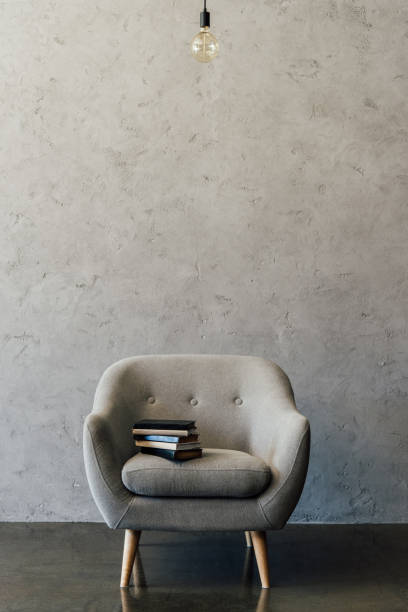 istock Cozy grey armchair with books and light bulb in empty room 696170726